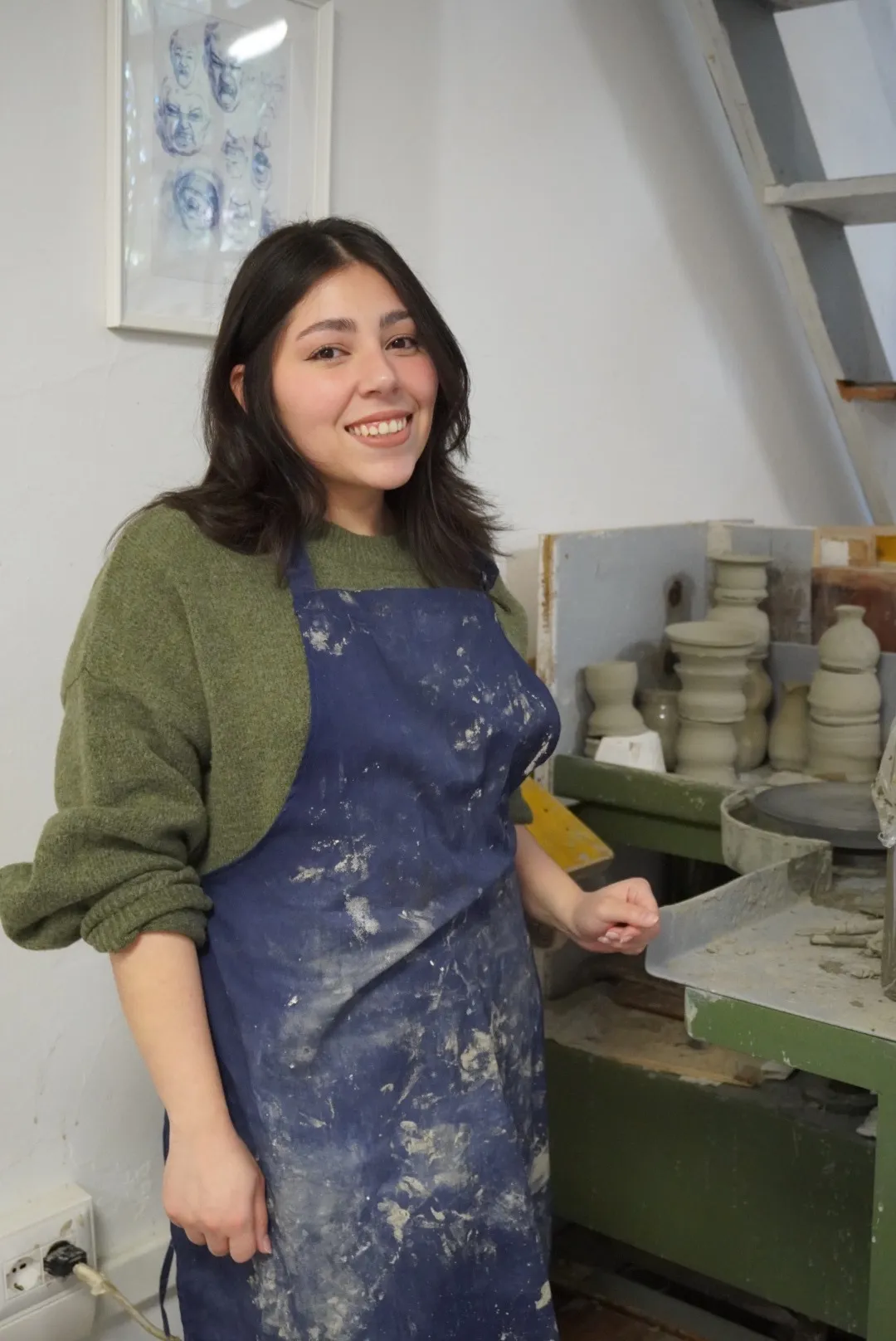 Frida en el taller de Florencia, con mandil de trabajo, junto al torno y las piezas recién hechas